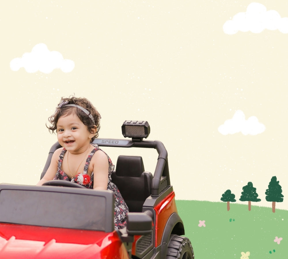 A young child with curly hair sits smiling in a red and black ride-on toy vehicle. The background is a stylized cream-colored sky with illustrated white clouds, green trees, and a grassy hill.